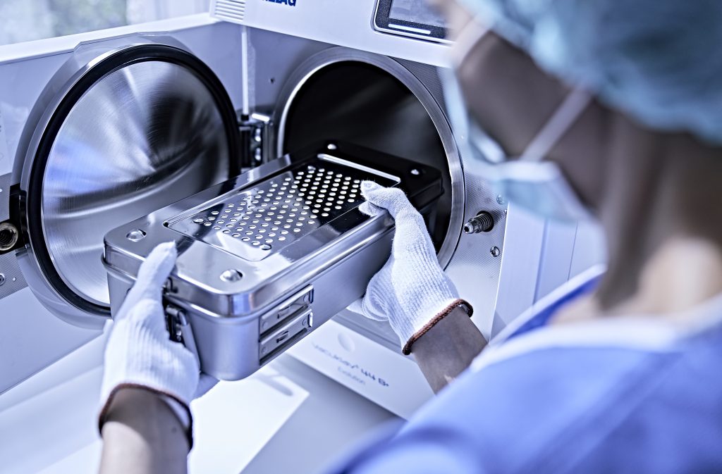 Medizinisches Personal legt sterile Instrumente in einen Autoklaven zur Sterilisation.